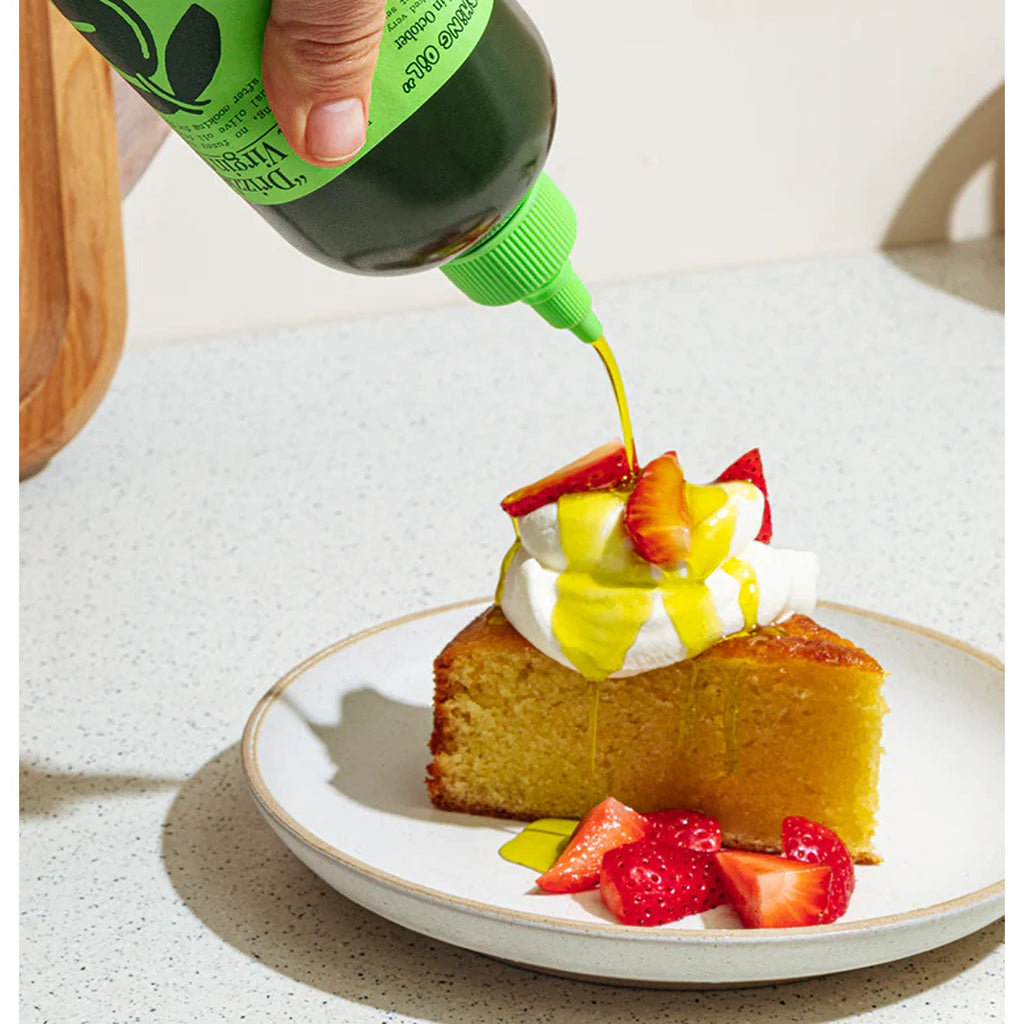 A sleek bottle of Graza Baby Drizzle olive oil, featuring a vibrant green label and a modern, ergonomic design. The olive oil is known for its rich, smooth flavor, perfect for drizzling over dishes or using as a finishing touch in cooking.