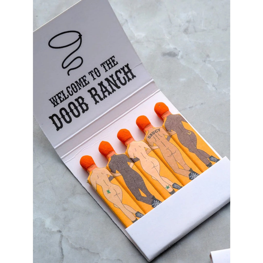 A matchbook from Doob Ranch, featuring a playful and rustic design on the cover. The matchbook contains several matchsticks and adds a touch of personality with its unique branding, perfect for lighting candles or creating a fun conversation piece.