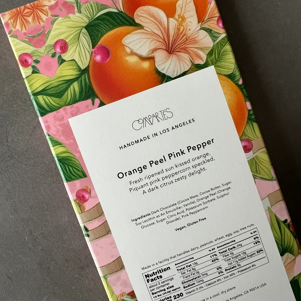 A dark chocolate bar with a rich texture, featuring pieces of orange peel and a hint of pink pepper for a unique and flavorful combination.